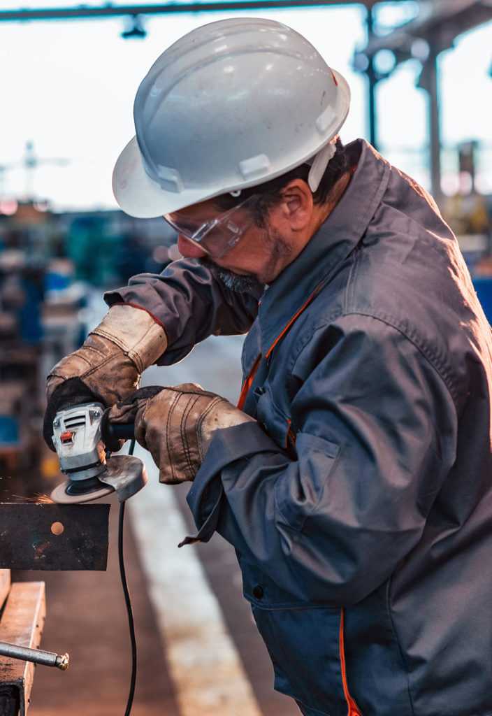 Skilled industrial worker grinding metal part